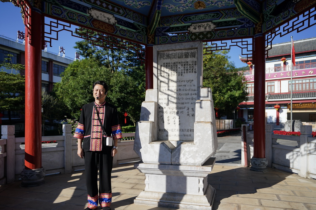 10月23日，一名講解員在云南省普洱市寧洱哈尼族彝族自治縣民族團結園內為游客介紹民族團結誓詞碑。