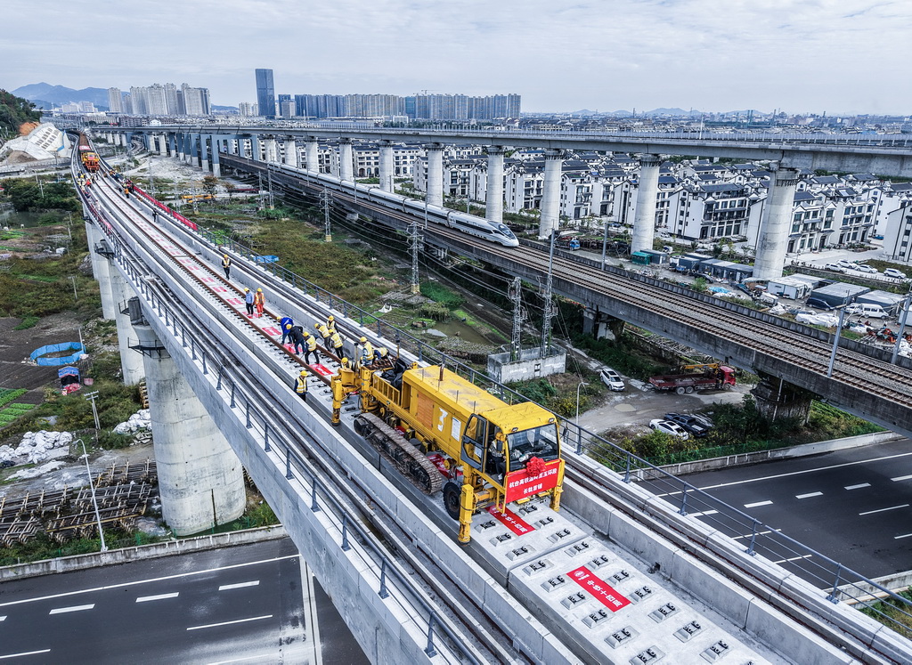 11月5日，在浙江省臺州市杭臺高鐵溫嶺至玉環段施工作業現場，中鐵十四局工作人員操作長軌牽引車進行鋪軌作業（無人機照片）。