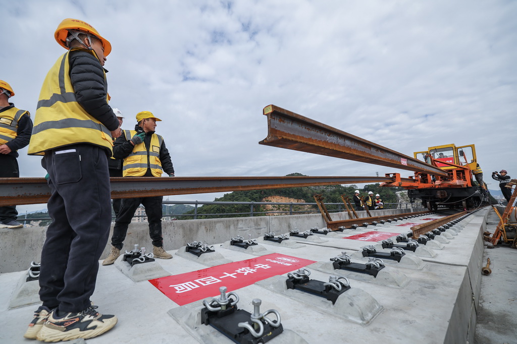 11月5日，在浙江省臺州市杭臺高鐵溫嶺至玉環段施工作業現場，中鐵十四局工作人員協助長軌牽引車進行鋪軌作業。