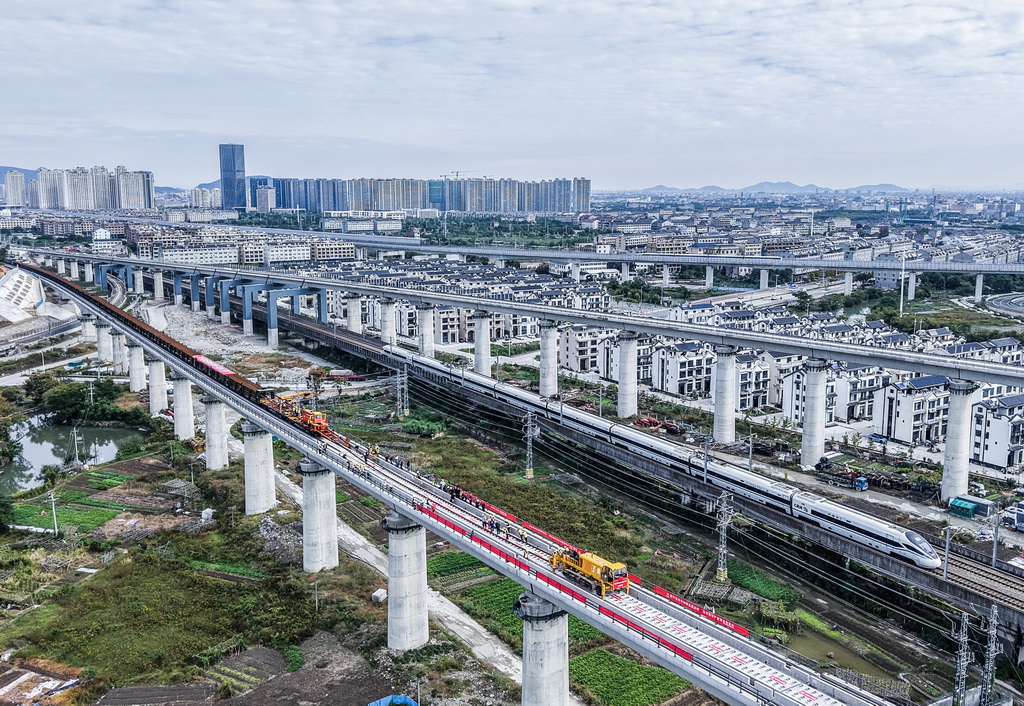 11月5日，在浙江省臺州市杭臺高鐵溫嶺至玉環段施工作業現場，中鐵十四局工作人員操作長軌牽引車進行鋪軌作業（無人機照片）。