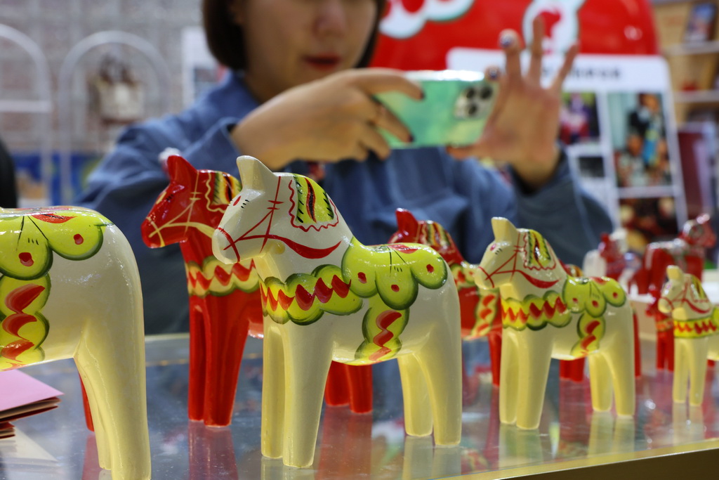 11月7日，在第八屆進博會消費品展區，參觀者在拍攝一組瑞典傳統手工藝達拉木馬展品。新華社記者 方喆 攝