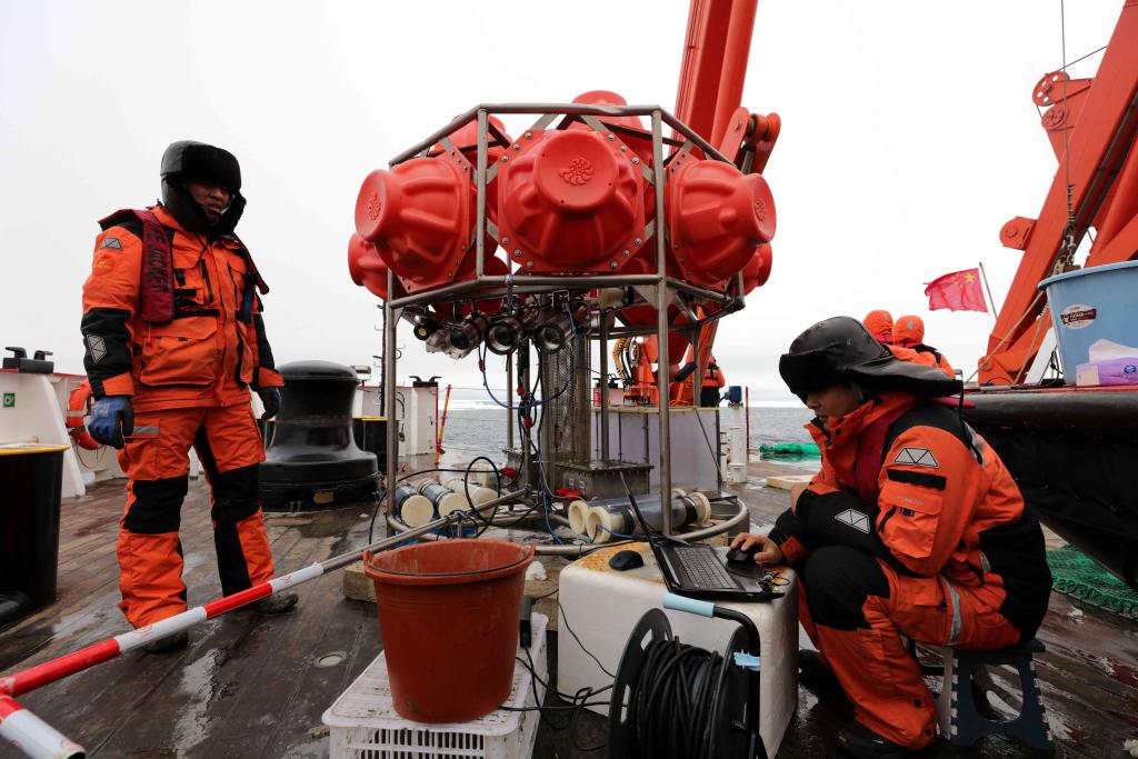 圖為劉坤（右）等科考隊員和剛回收到船上的海底生物影像觀測系統。新華社記者 劉詩平 攝